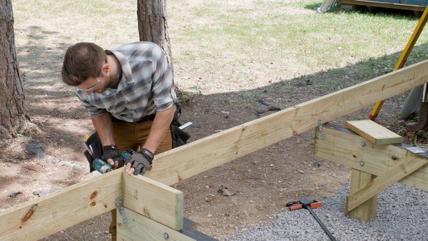 person fastening blocking through the side of the rim joist