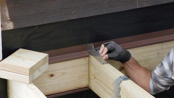 person using an angle bracket to align joist and ledger board