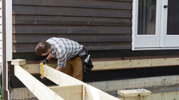 person using speed square to plumb the joist