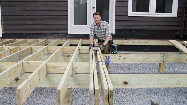 person attaching breaker board in the middle of a deck frame