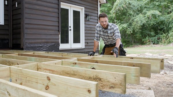 person standing by deck frame after all joists have been attached