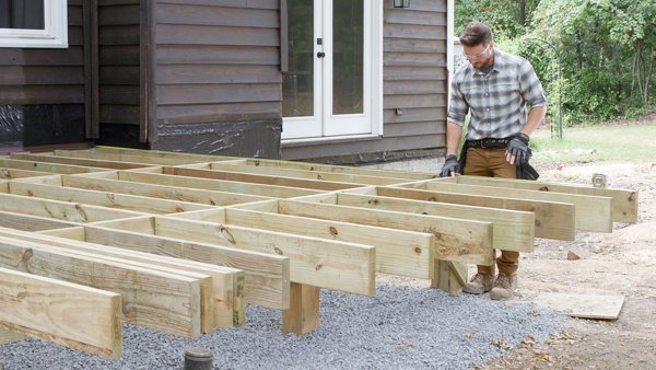 person using tape measure to measure from house to outside rim joist