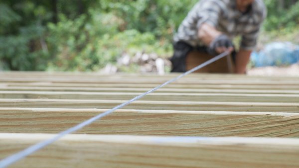 person using chalk line to mark where joists need to be cut
