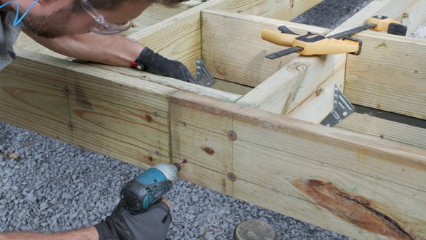person adding screws through front of rim joist to the block