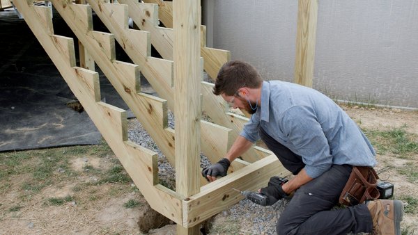 A man installing stair stringers for a deck.