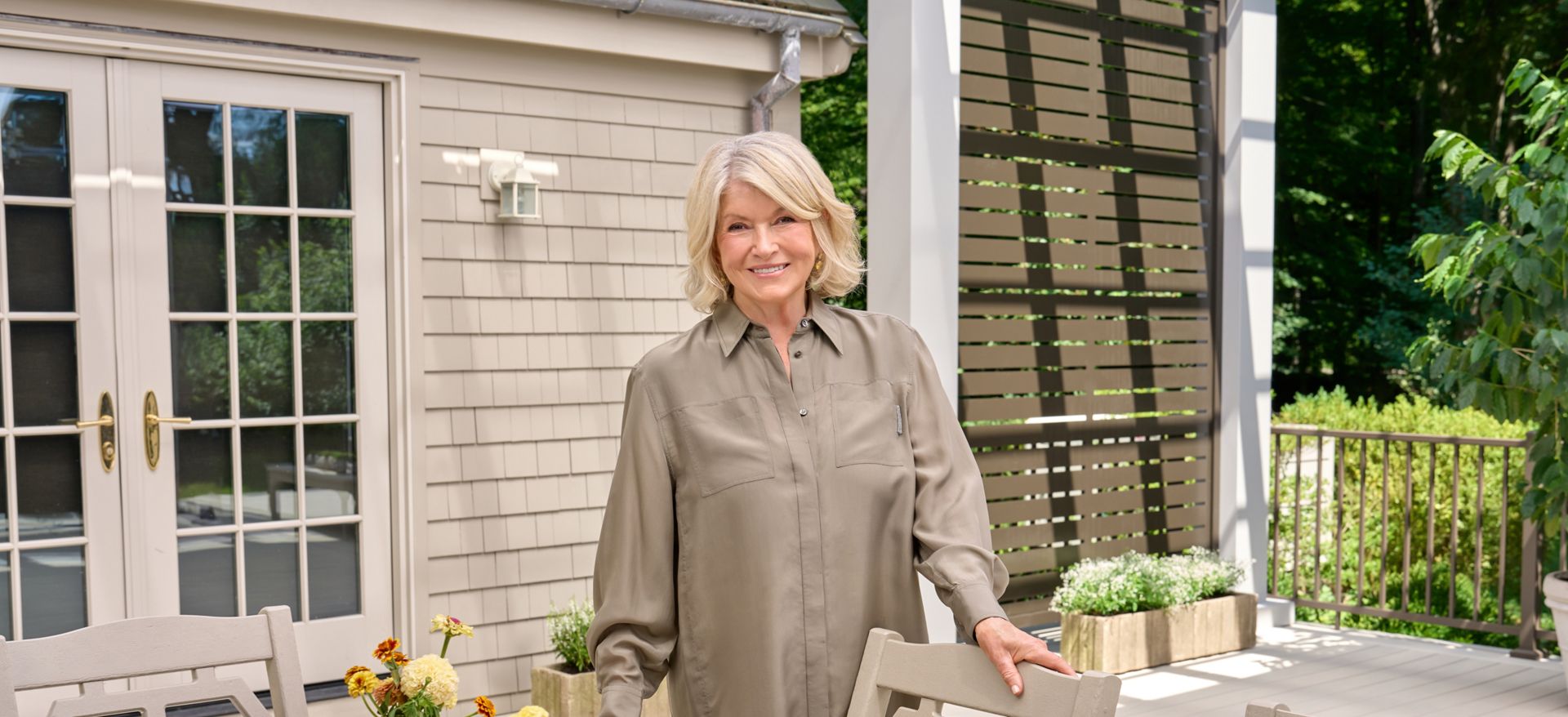 Martha Stewart standing on her new Trex deck with a beautifully arranged table and her pergola decorating behind her.
