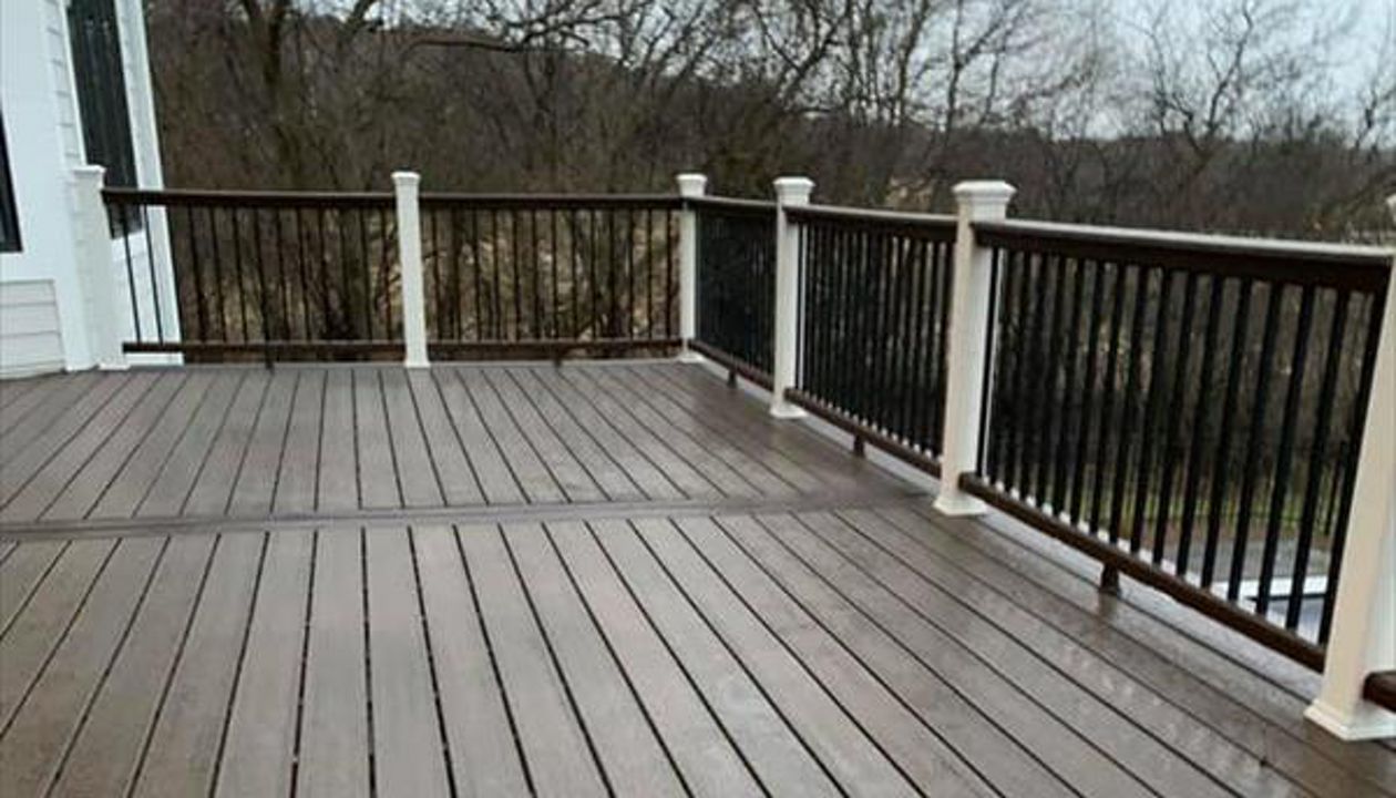 This deck features Trex transcend spice rum as the main decking and drink rail and Trex transcend vintage lantern for the picture frame and middle divider. It has Trex transcend railing that consists of white post sleeves, vintage lantern top/bottom rail.