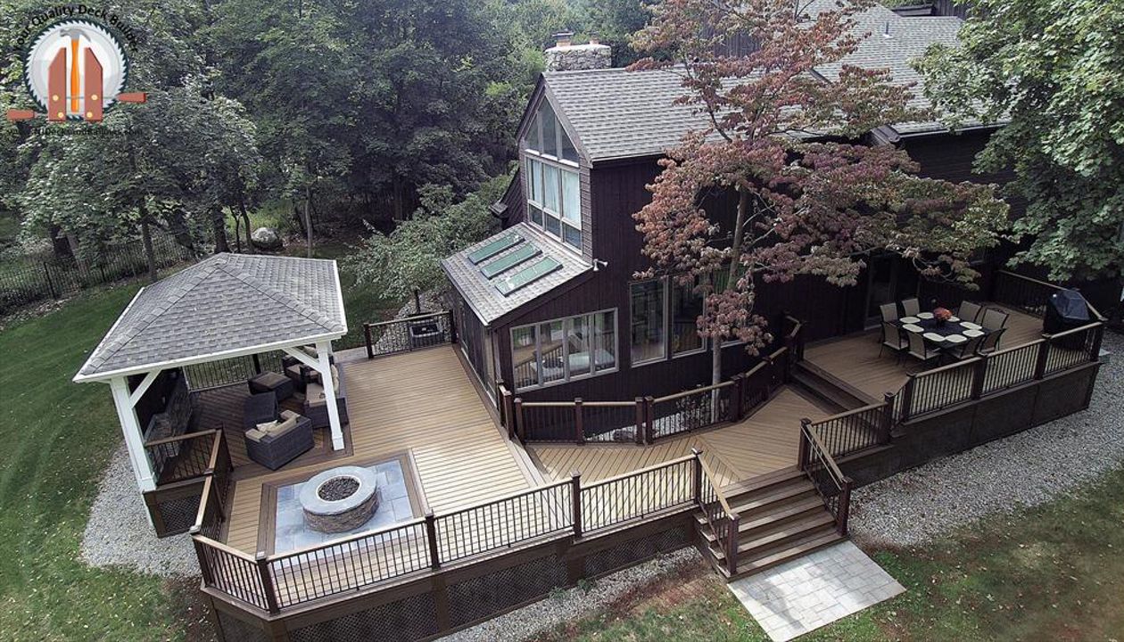 Custom designed deck in Trex Transcend Havana Gold decking with Spiced Rum border and Signature Bronze aluminum railings. This deck has a fire pit area and a covered pavilion and is located in Upper Saddle River, NJ.