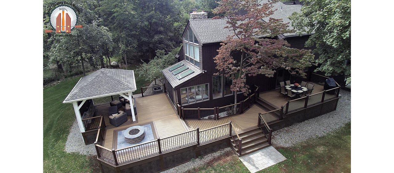 Custom designed deck in Trex Transcend Havana Gold decking with Spiced Rum border and Signature Bronze aluminum railings. This deck has a fire pit area and a covered pavilion and is located in Upper Saddle River, NJ.