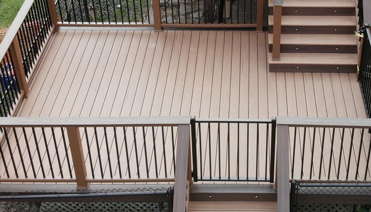 Transcend Decking in Tiki Torch with a Lava Rock picture frame, Transcend Tree House Handrail with Lava Rock Coctail Top and Black aluminum balusters,  Black aluminum gate, stair lighting, and Lava Rock fascia.