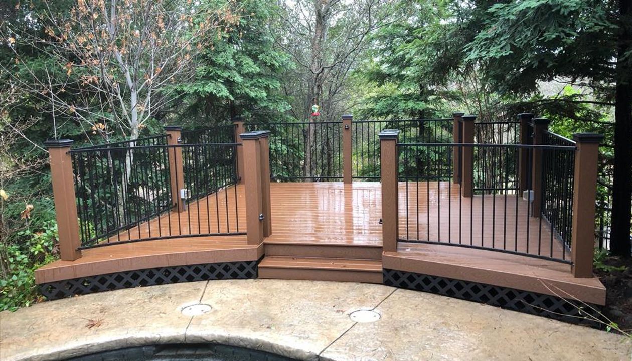 Custom Trex deck in Saddle in Redding,with hidden fasteners, custom railing, and black lattice skirting in a backyard.  Majestic Builders is proud to provide top quality composite decks that will last a lifetime.