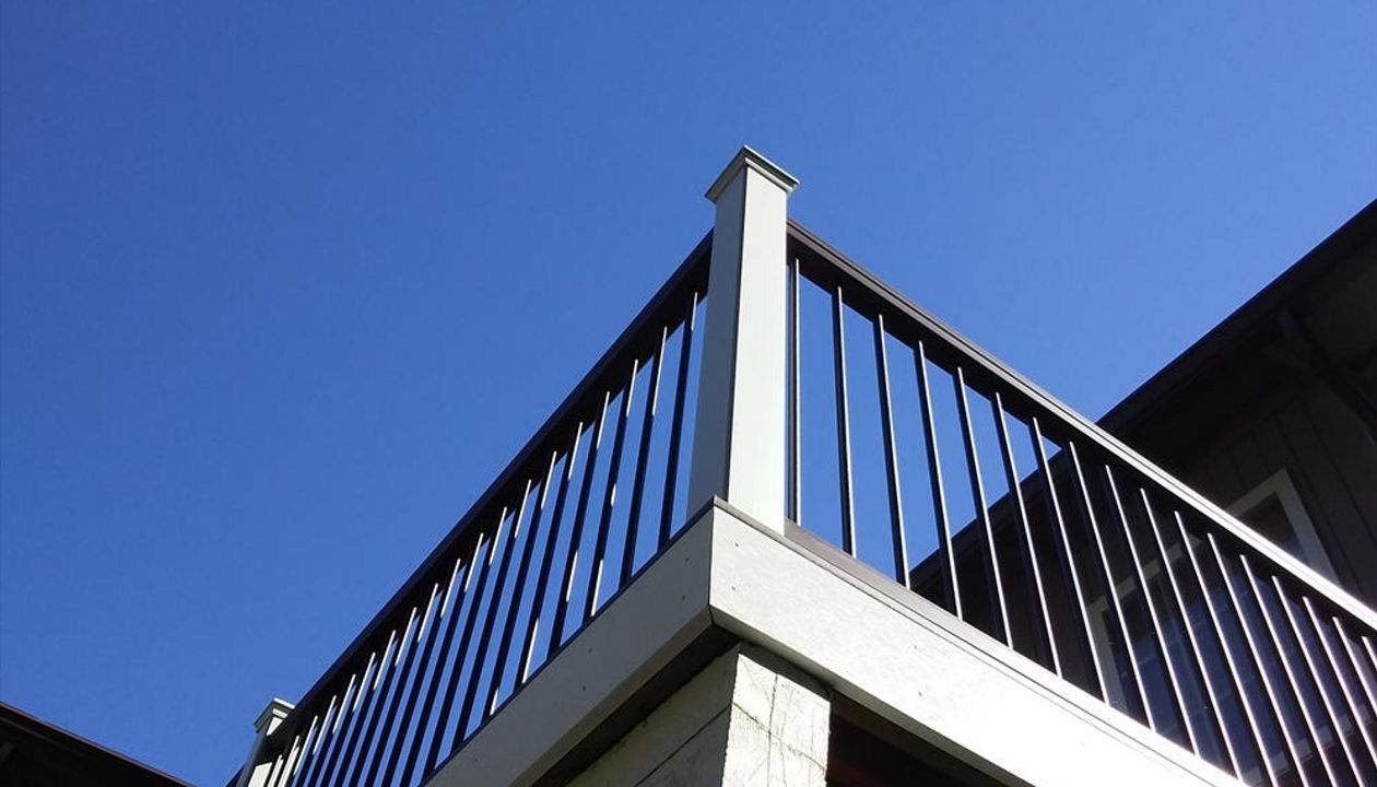 Trex Transcend composite rail in Vintage Lantern rail cap, black aluminum balusters, and white composite sleeves and caps.