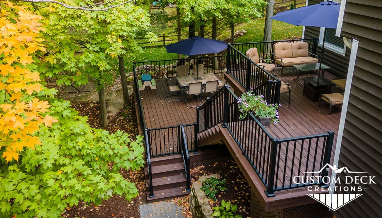 Multi-tiered Trex Transcend Lava Rock deck built with matching Lava Rock picture frame, fascia and composite lattice. Railing is black Trex Signature aluminum.