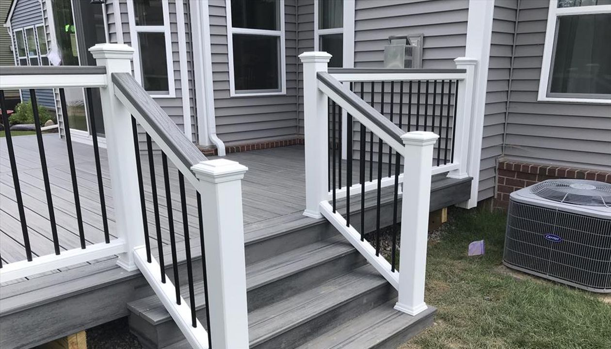 Deck in New Hudson, MI., constructed out of Trex Transcend Tropical decking in Island Mist and complimented by Classic White Trex railing with black balusters and Classic White privacy wall.
