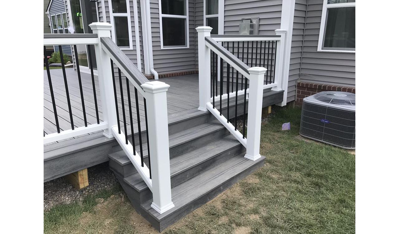 Deck in New Hudson, MI., constructed out of Trex Transcend Tropical decking in Island Mist and complimented by Classic White Trex railing with black balusters and Classic White privacy wall.