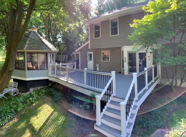 This deck features white transcend railing with black square aluminum balusters. It consists of Trex select pebble grey as the main decking and Trex transcend island mist as the picture frame, middle divider, and drink rail.
