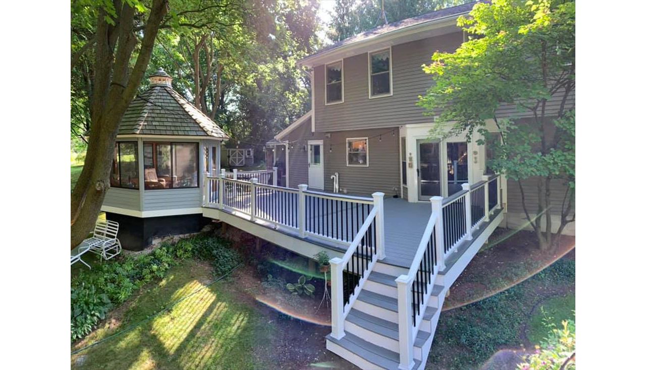 This deck features white transcend railing with black square aluminum balusters. It consists of Trex select pebble grey as the main decking and Trex transcend island mist as the picture frame, middle divider, and drink rail.