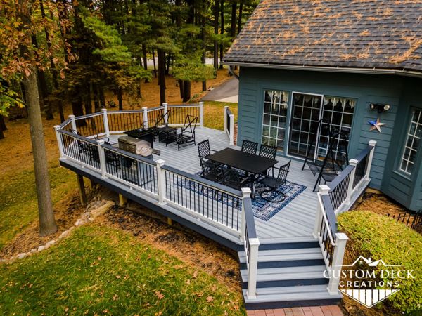 Trex Select Pebble Grey Deck, built with white Trex Select composite railing, black round aluminum balusters, and matching Winchester Grey cocktail board.