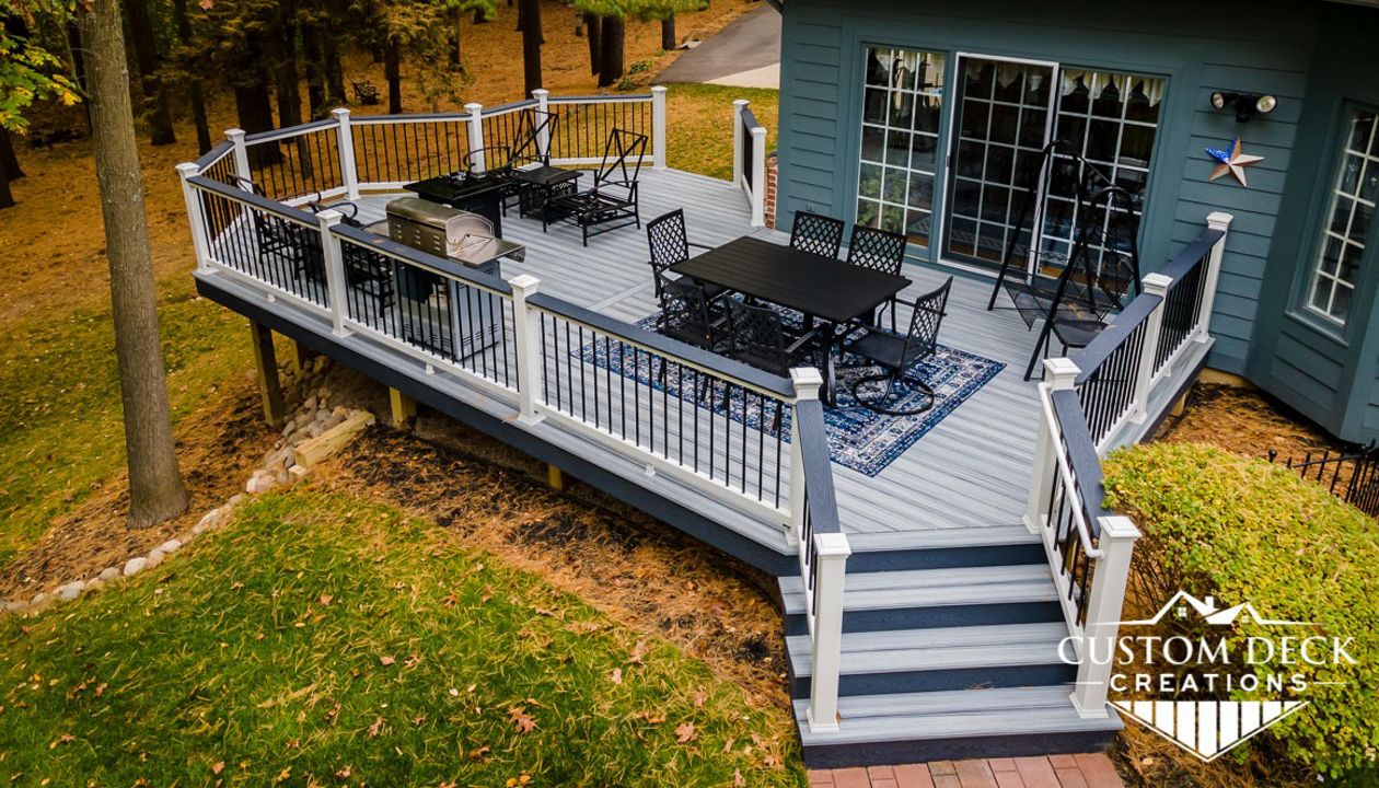 Trex Select Pebble Grey Deck, built with white Trex Select composite railing, black round aluminum balusters, and matching Winchester Grey cocktail board.
