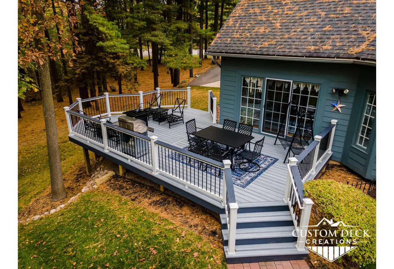 Trex Select Pebble Grey Deck, built with white Trex Select composite railing, black round aluminum balusters, and matching Winchester Grey cocktail board.