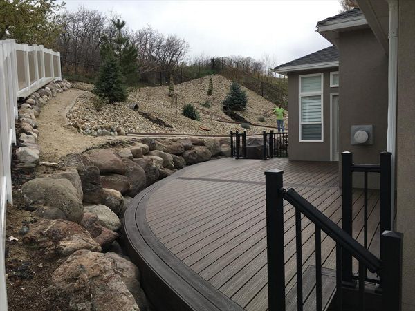 Trex decking with Spiced rum and vintage lantern curved borders. Giving this customer a unique deck to match his retaining wall and giving as much deck space as possible.