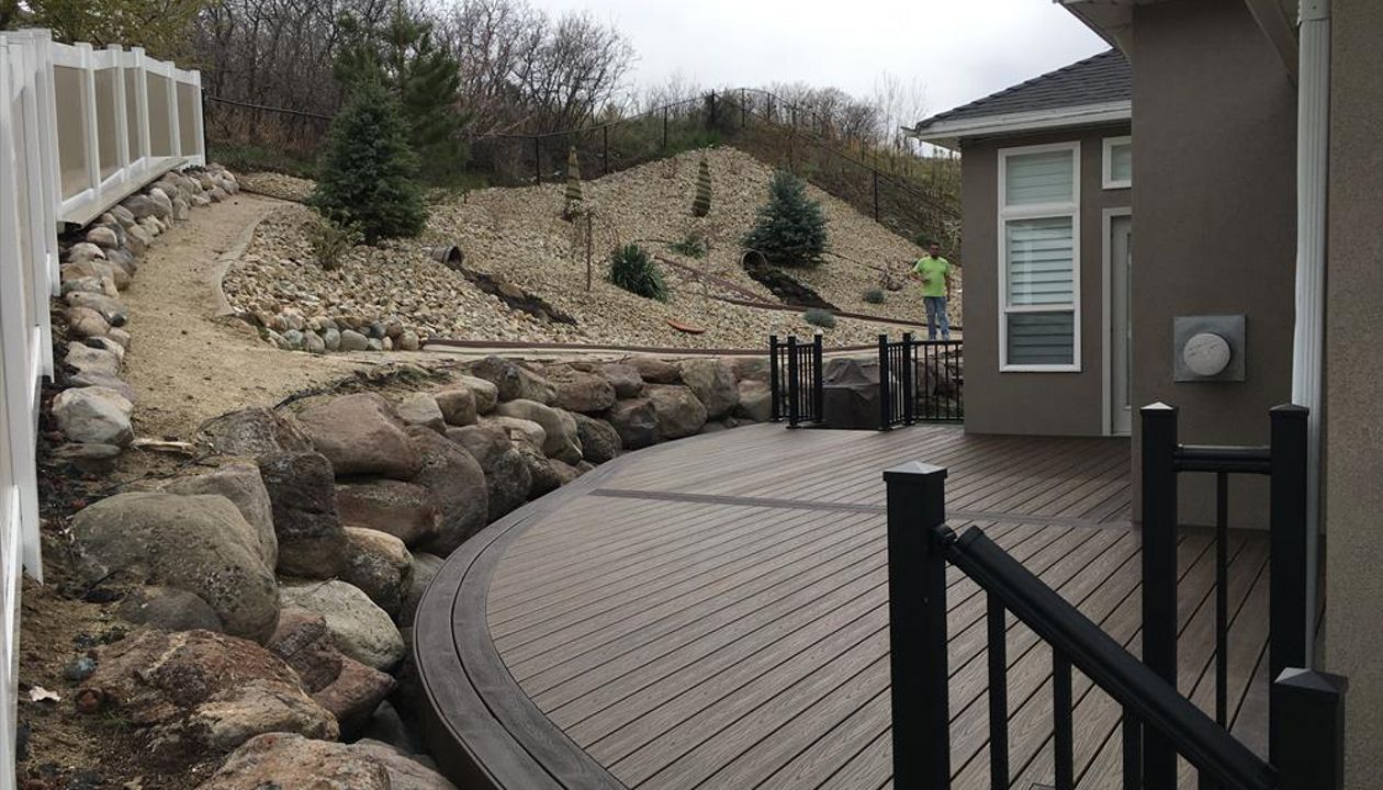 Trex decking with Spiced rum and vintage lantern curved borders. Giving this customer a unique deck to match his retaining wall and giving as much deck space as possible.