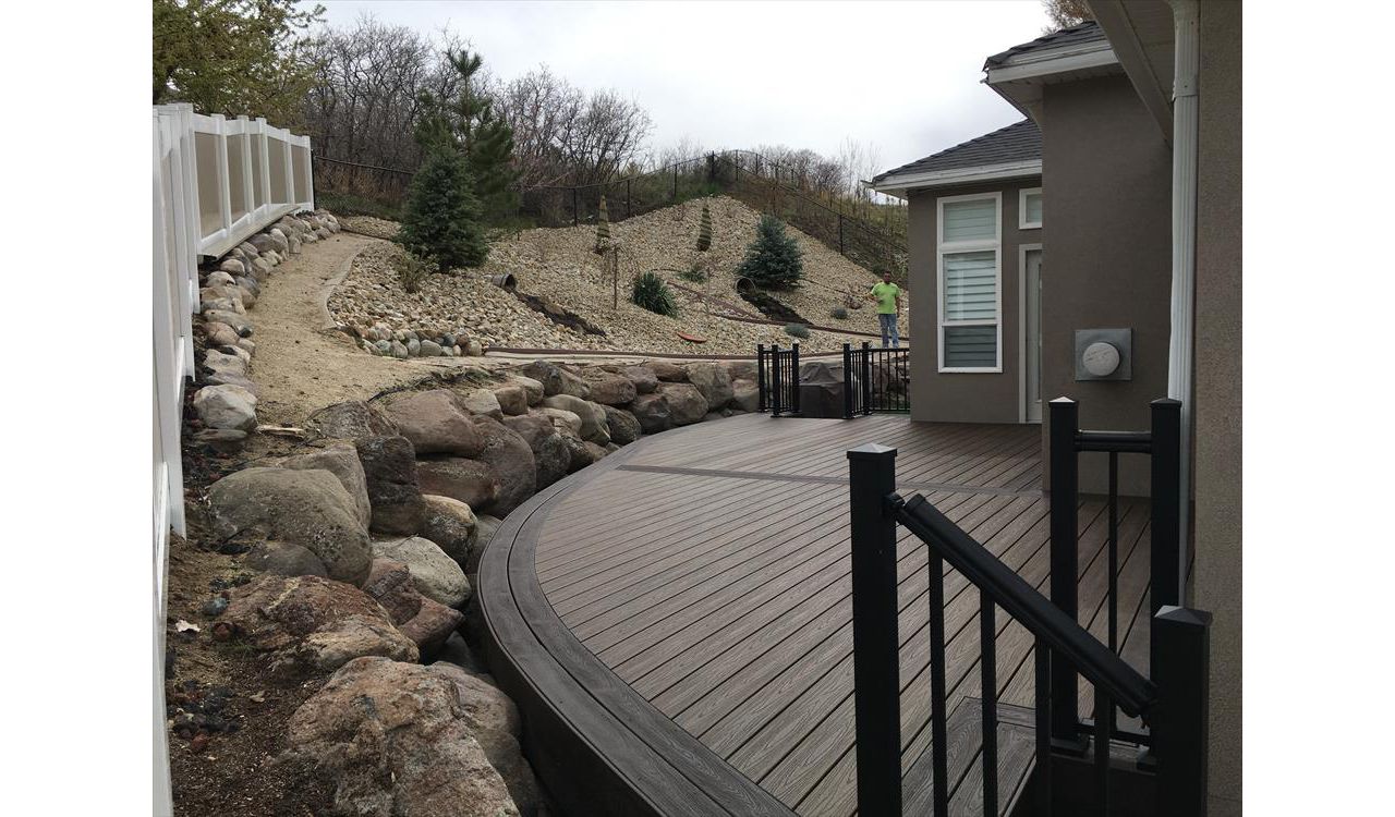 Trex decking with Spiced rum and vintage lantern curved borders. Giving this customer a unique deck to match his retaining wall and giving as much deck space as possible.