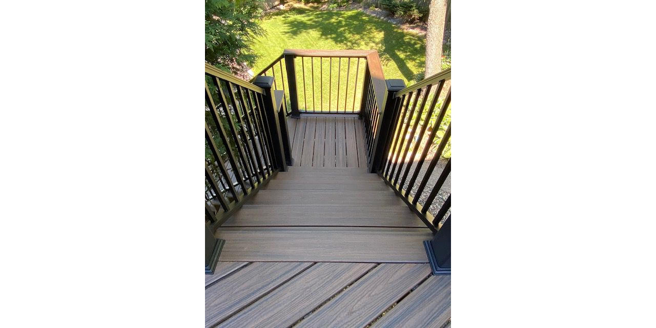 Trex/Transcend/Spiced Rum/Composite Decking with Trex/Signature/Aluminum Railing (black) between Trex/Composite Post Sleeves (black) and Trex/Transcend/Spiced Rum/Composite Decking/Drink Rail