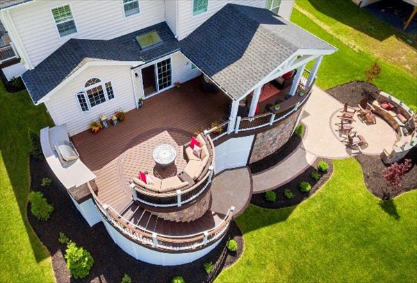 Trex Transcend Spiced Rum Deck with Vintage Lantern border.   White Trex Transcend Rail with Spiced Rum top rail and black aluminum balusters.   Wolf board skirting and custom stone wall skirting, Custom Roof, Kitchen and Patio with Fireplace.