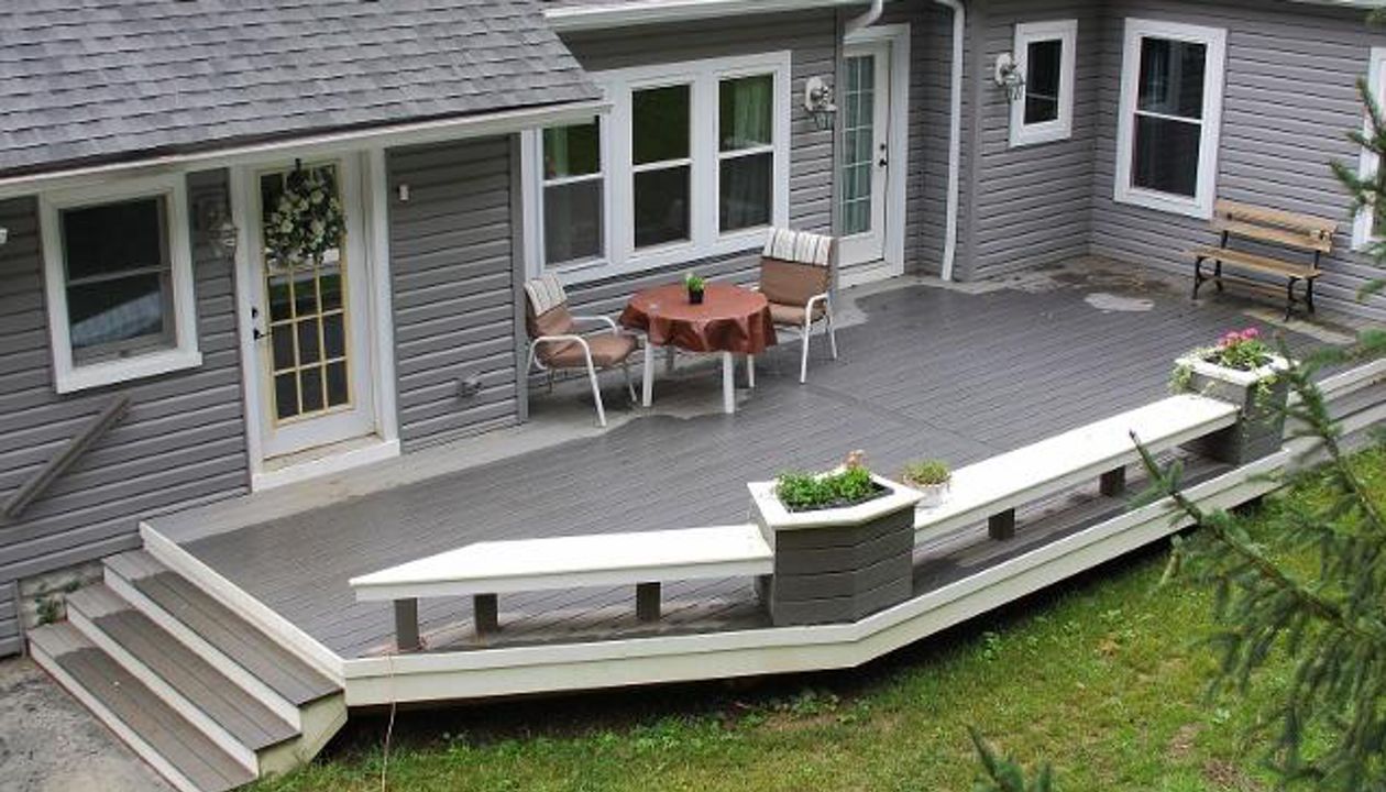 Ground level deck featuring Trex Enhance Clam Shell decking with custom built in benches and flower pots.