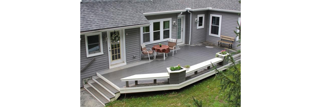 Ground level deck featuring Trex Enhance Clam Shell decking with custom built in benches and flower pots.