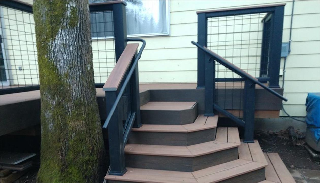 Custom designed sweeping staircase with Trex Transcend Cocktail Railings, Trex ADA handrails, Trex Savanna Gold decking, Lava Rock accents, wire infill rail panels