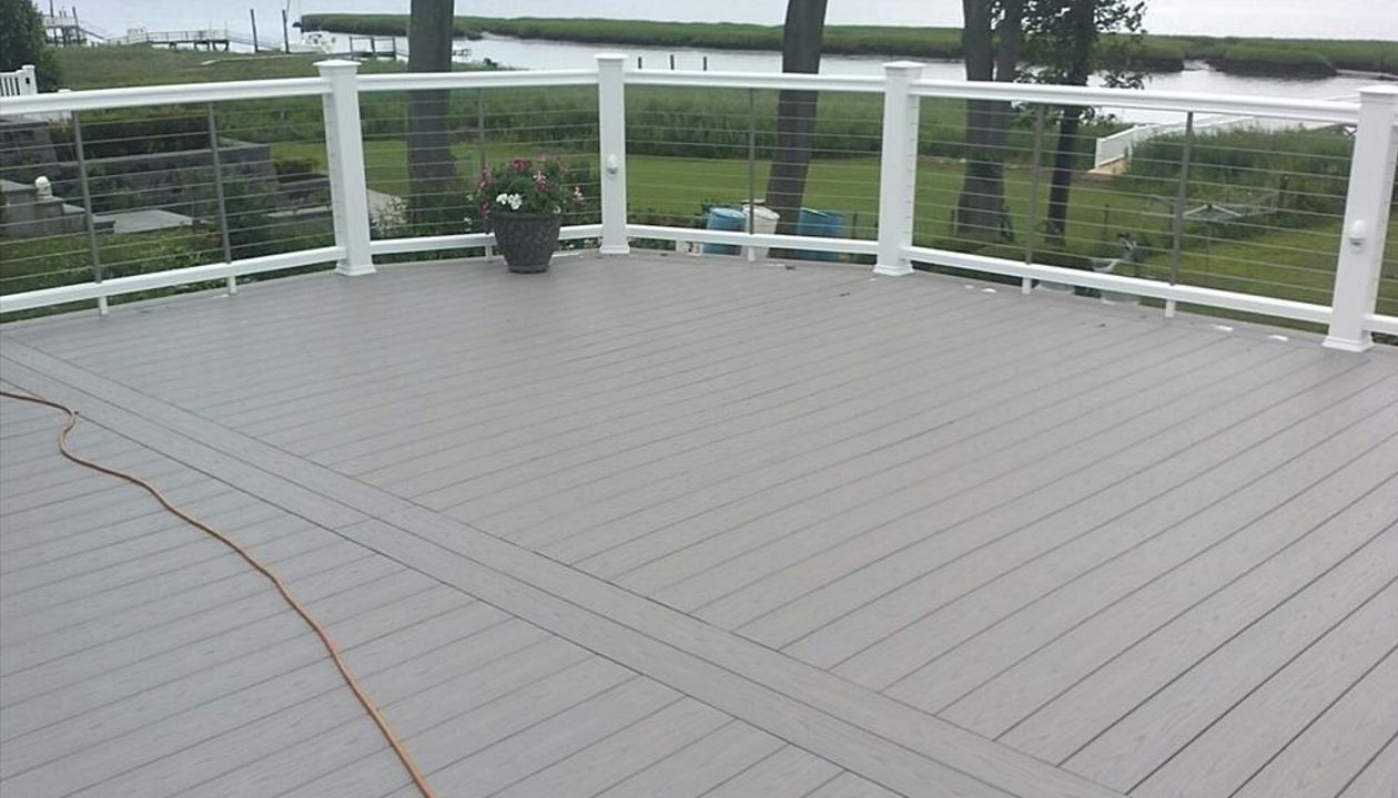 Trex Select Pebble Grey Decking  was used on this Trex Deck.  Cable Rail is stainless steel. Rain Escapes helped to create usable living space under the deck. Custom Lattice was used to create a storage space under the custom deck in Westport CT