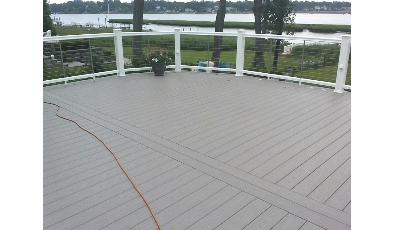 Trex Select Pebble Grey Decking  was used on this Trex Deck.  Cable Rail is stainless steel. Rain Escapes helped to create usable living space under the deck. Custom Lattice was used to create a storage space under the custom deck in Westport CT
