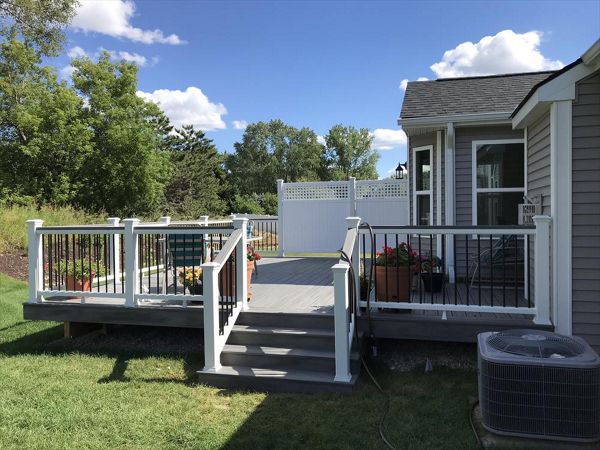 Deck in New Hudson, MI., constructed out of Trex Transcend Tropical decking in Island Mist and complimented by Classic White Trex railing with black balusters and Classic White privacy wall.