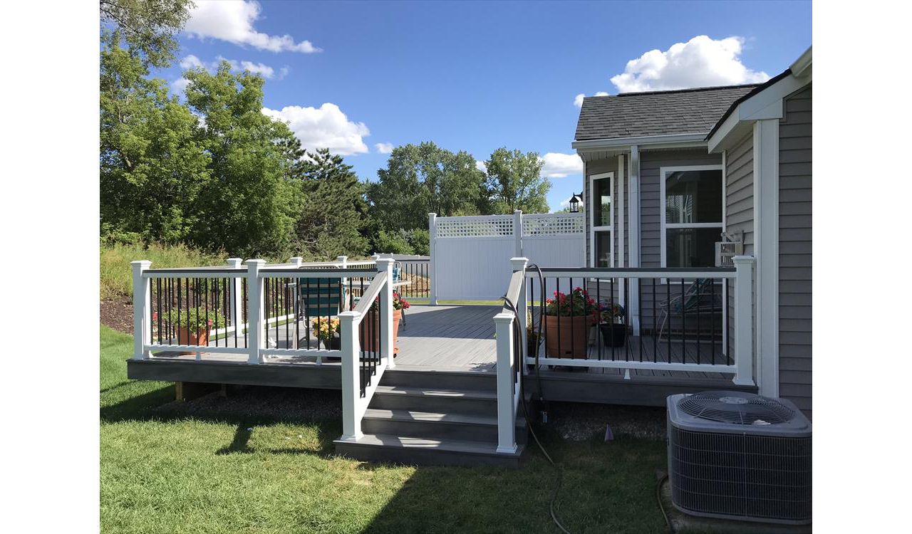 Deck in New Hudson, MI., constructed out of Trex Transcend Tropical decking in Island Mist and complimented by Classic White Trex railing with black balusters and Classic White privacy wall.