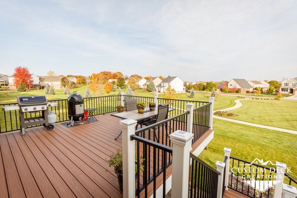 Trex Transcend Tiki Torch decking with white Azek PVC fascia. Railing is Trex Signature aluminum in black, with white Trex composite railing posts. Solar powered railing post cap lights.
