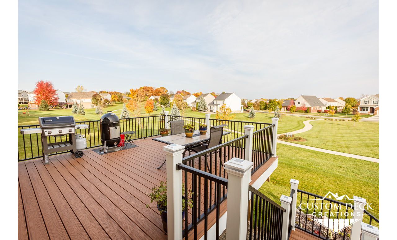 Trex Transcend Tiki Torch decking with white Azek PVC fascia. Railing is Trex Signature aluminum in black, with white Trex composite railing posts. Solar powered railing post cap lights.