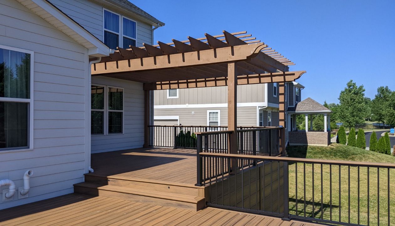 Trex Transcend Havana Gold, Signature rail in Charcoal Black, custom stained cedar pergola. Trex riser and flush mount lights.