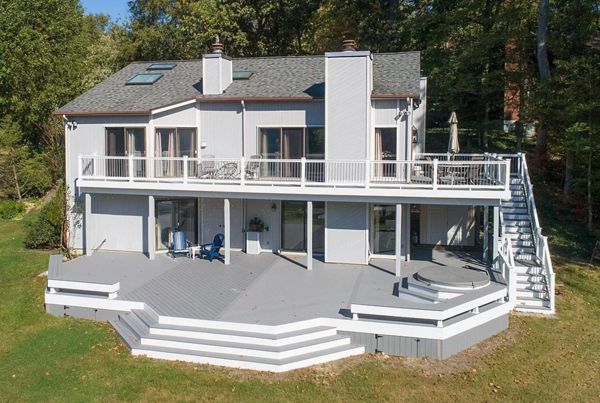 Trex Select Pebble Gray composite decking, white vinyl railing, gray round aluminum balusters, white fascia and vertical skirting