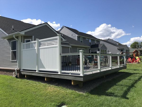 Deck in New Hudson, MI., constructed out of Trex Transcend Tropical decking in Island Mist and complimented by Classic White Trex railing with black balusters and Classic White privacy wall.