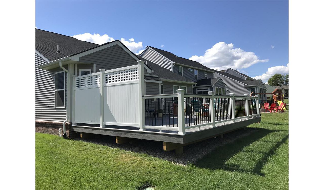 Deck in New Hudson, MI., constructed out of Trex Transcend Tropical decking in Island Mist and complimented by Classic White Trex railing with black balusters and Classic White privacy wall.