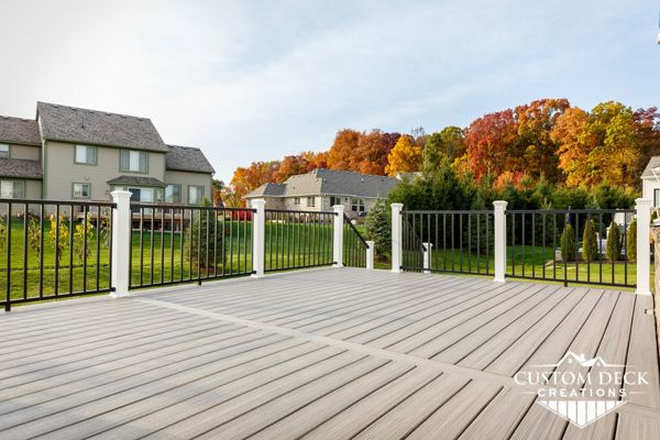 Trex Enhance Naturals Rocky Harbor decking with Trex Signature aluminum railing in black, with white composite Trex railing posts. Deck was wider than the longest decking board, so to avoid any unsightly butt joints a parting board was installed.