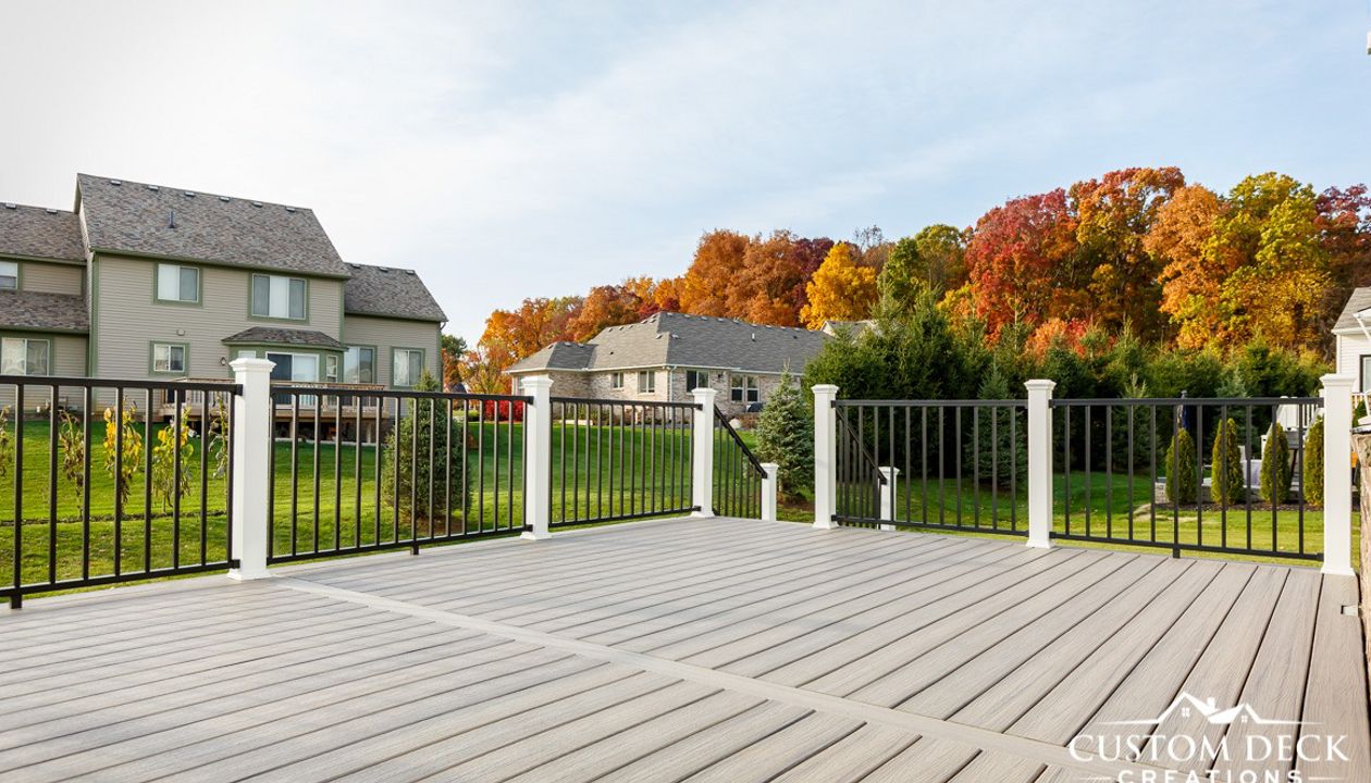 Trex Enhance Naturals Rocky Harbor decking with Trex Signature aluminum railing in black, with white composite Trex railing posts. Deck was wider than the longest decking board, so to avoid any unsightly butt joints a parting board was installed.
