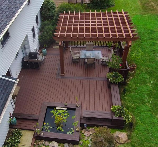 Ground level Asian garden deck featuring Trex Transcend Fire Pit decking, custom Vintage lantern boarder, Cedar Pergola, Koi pond, and Transcend Vintage Lantern railing.