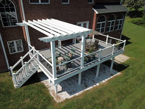 Trex Select Pebble Gray Composite Deck with Trex Composite Railing with black aluminum balusters and a White Vinyl Pergola