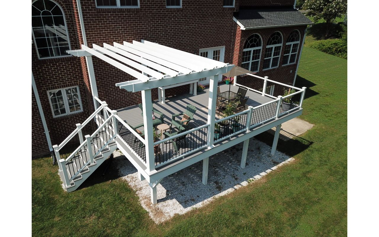 Trex Select Pebble Gray Composite Deck with Trex Composite Railing with black aluminum balusters and a White Vinyl Pergola