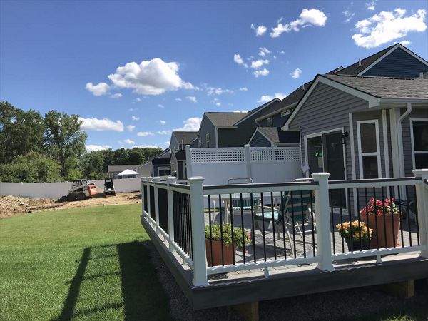 Deck in New Hudson, MI., constructed out of Trex Transcend Tropical decking in Island Mist and complimented by Classic White Trex railing with black balusters and Classic White privacy wall.