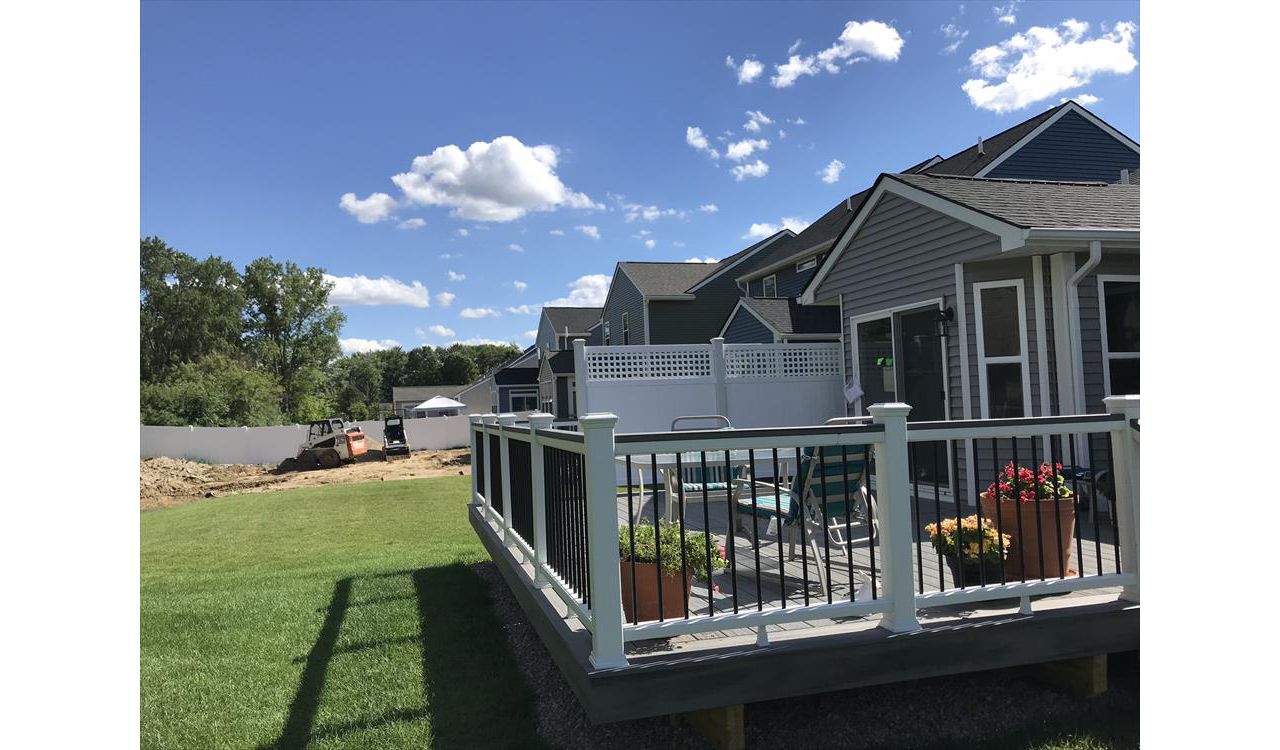Deck in New Hudson, MI., constructed out of Trex Transcend Tropical decking in Island Mist and complimented by Classic White Trex railing with black balusters and Classic White privacy wall.
