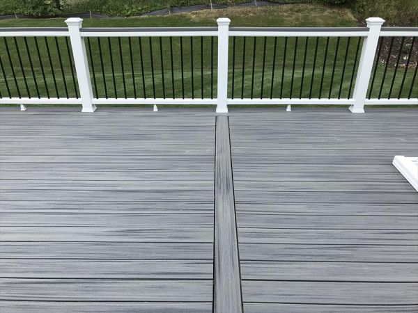 Deck in New Hudson, MI., constructed out of Trex Transcend Tropical decking in Island Mist and complimented by Classic White Trex railing with black balusters and Classic White privacy wall.